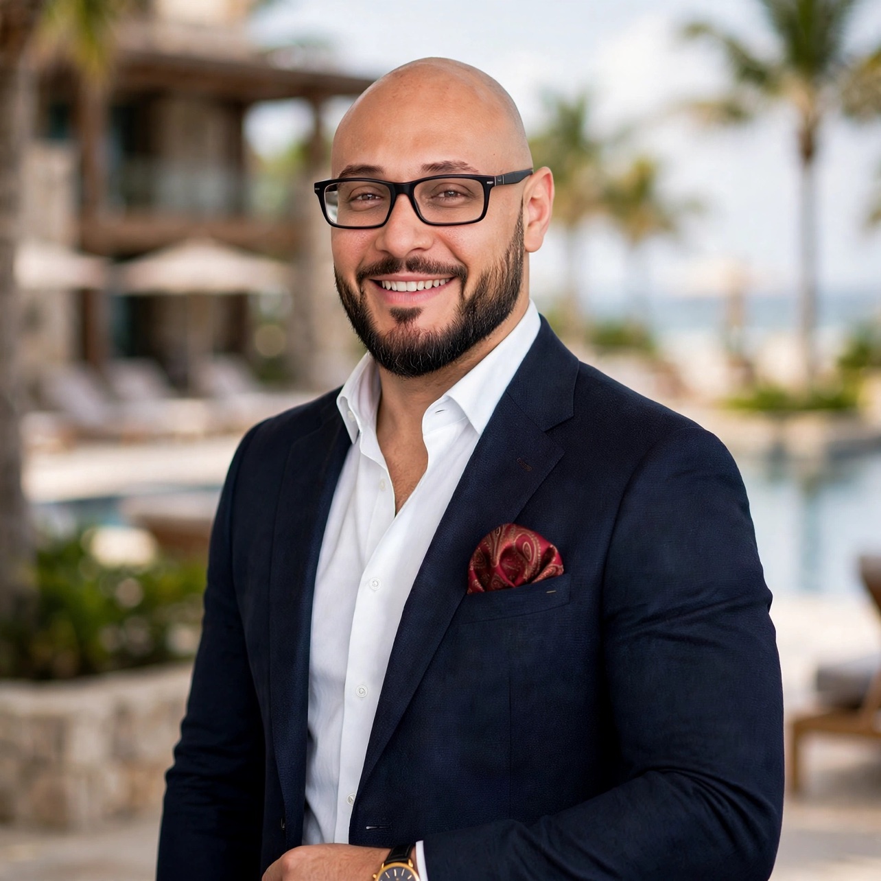 Abdul Aboushadi, Principal of Castellan Hospitality Advisors, in a navy suit with a white open-collar shirt and red paisley pocket square
