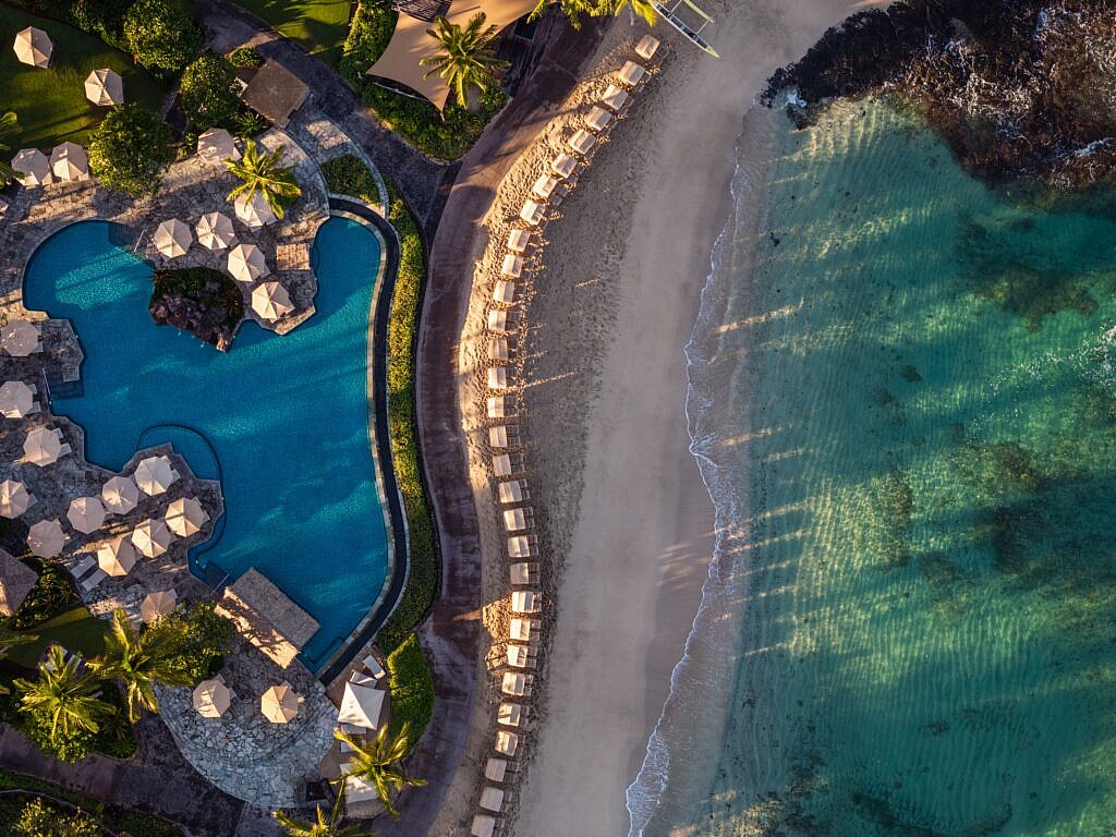 Luxury resort in Hawaii with palm trees and pool at sunset